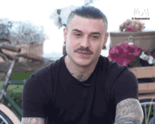 a man with a mustache is wearing a black t-shirt and earrings