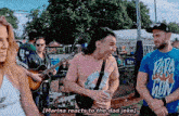 marina reacts to the dad joke while standing next to a man playing a guitar