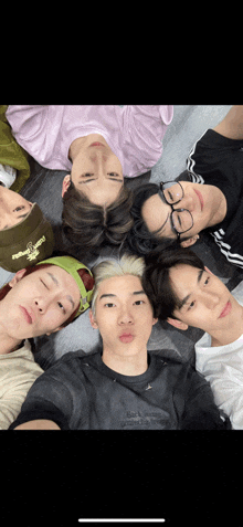 a group of young men are laying in a circle with one wearing a green headband that says " i love you " on it