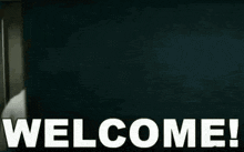 a man is standing in front of a wall with the words welcome ! on it .