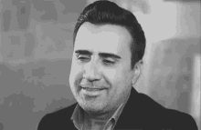 a man with a beard is smiling in a black and white photo .