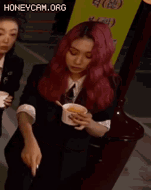 a woman with red hair is holding a cup of soup with a spoon .