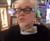 a man with glasses and a hot dog in a tin foil wrapper