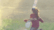 a woman in a red and white sweater is running through a grassy field