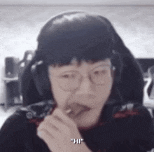 a man wearing headphones and glasses is eating a piece of chocolate .