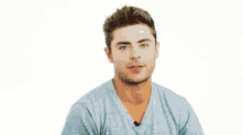 a young man wearing a blue t-shirt is making a funny face .