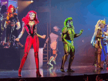 a group of people dressed in costumes are dancing on stage