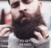 a man with a beard is trimming his beard with a pair of scissors and a ring .