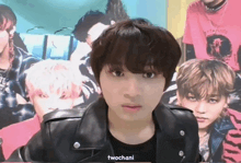 a young man wearing a black shirt and a black leather jacket is standing in front of a group of boys ..