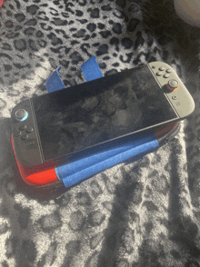 a nintendo switch is in a case on a leopard print blanket