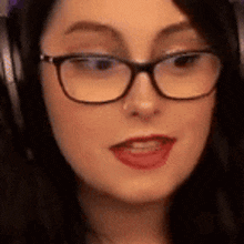 a woman wearing glasses and headphones is looking at the camera and making a funny face .