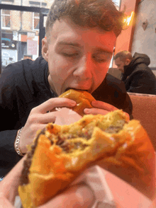 a man is eating a hamburger in a restaurant with a sign that says ' a ' on it