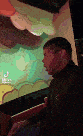 a man in a black jacket is standing in front of a wall with balloons on it .