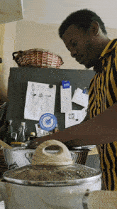 a man in a yellow and black striped shirt cooking in front of a refrigerator