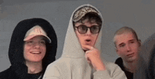 a group of young men wearing hoodies and hats are standing next to each other .