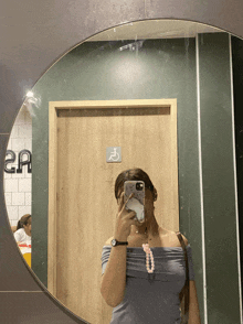 a woman is taking a picture of herself in a mirror in front of a handicapped stall
