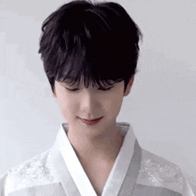 a young man wearing a white kimono is smiling .