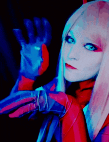a woman in a red and blue costume holds her hand up in the air