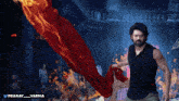 a man holding a red cloth in front of a fire with the hashtag pranay_varma below him