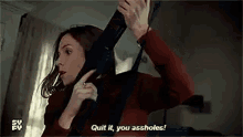 a woman is holding a gun in her hand and talking on the phone .