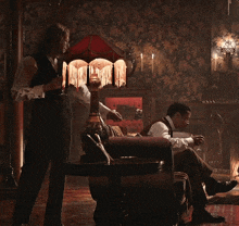 a man sits on a couch in a dark room with a lamp and a lampshade