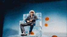 a man with curly hair is sitting on a throne made of ice cubes .