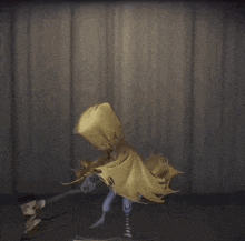 a statue of a person with a yellow cape holding a hammer