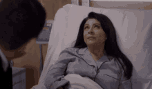 a woman is laying in a hospital bed talking to a man