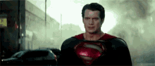 a man in a superman costume is standing in a city street .