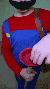 a man in a mario costume is holding a red plunger