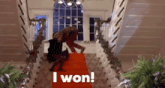 a man and a woman are standing on a red carpet on a staircase .