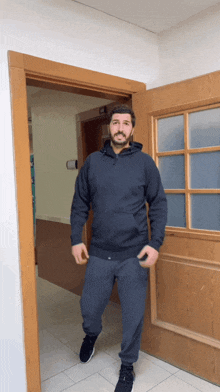 a man in a black hoodie stands in front of an open door