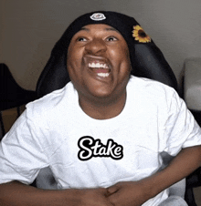 a man wearing a black beanie and a white shirt with the word stake on it