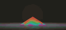 a rainbow colored pyramid is sitting on a dark surface