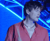 a man in a red shirt is standing in front of a blue light