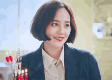 a woman wearing a blue jacket and a white shirt with leaf written on the collar
