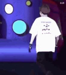 a man in a white t-shirt is walking on a stage with circles in the background .