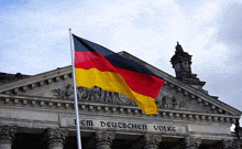 a german flag is flying in front of a building that says dem deutschen volke