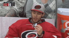 a man in a carolina hurricanes jersey is eating a candy bar