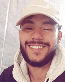a man with a beard is wearing a nike hat and smiling