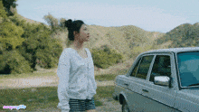 a woman standing next to a car with a watermark that says nexengirls on the bottom