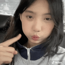 a young girl is making a funny face and pointing at her zipper ..