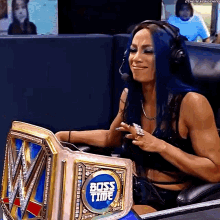 a woman with blue hair is sitting in a chair with a boss time belt on her lap .