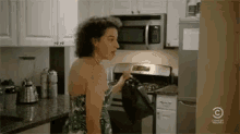 a woman is standing in a kitchen with a microwave and a stove .