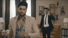 a man in a suit and tie is talking on a cell phone while another man in a suit stands behind him