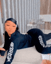 a woman in a black outfit is laying on her stomach on a couch .