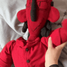 a person is touching a stuffed red devil with a black horn