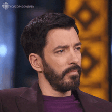 a man with a beard is wearing a purple shirt and a purple suit jacket