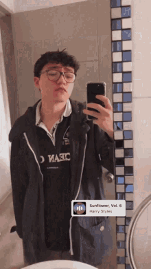 a young man taking a picture of himself in front of a mirror with a harry styles song playing on the phone