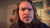 a man with long hair and a beard is making a face